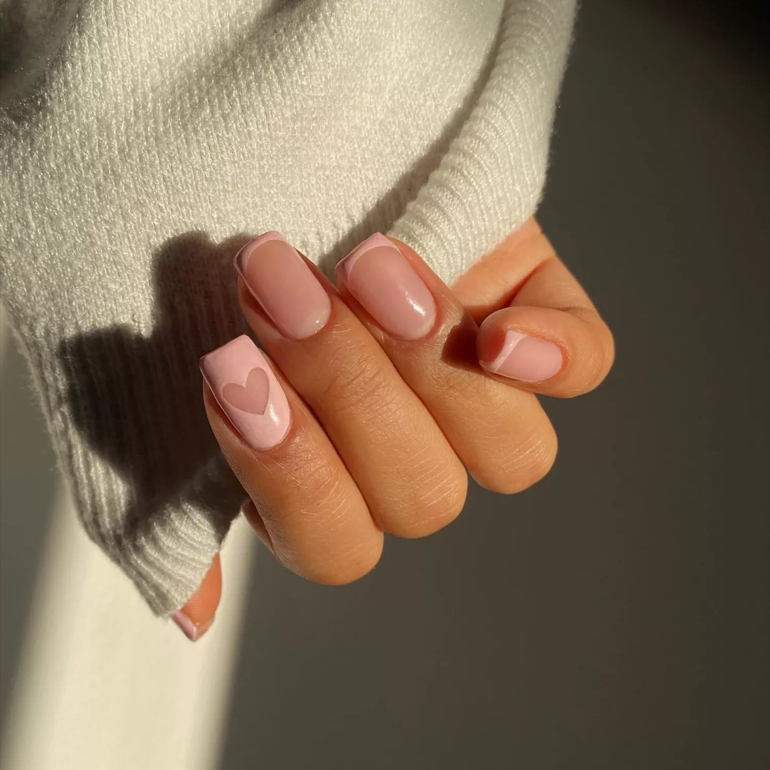 close up of short nail manicure with blush pink polish and heart