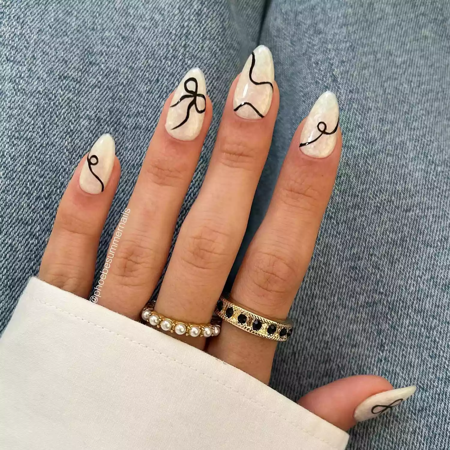 White chrome nails with thin black bow accent