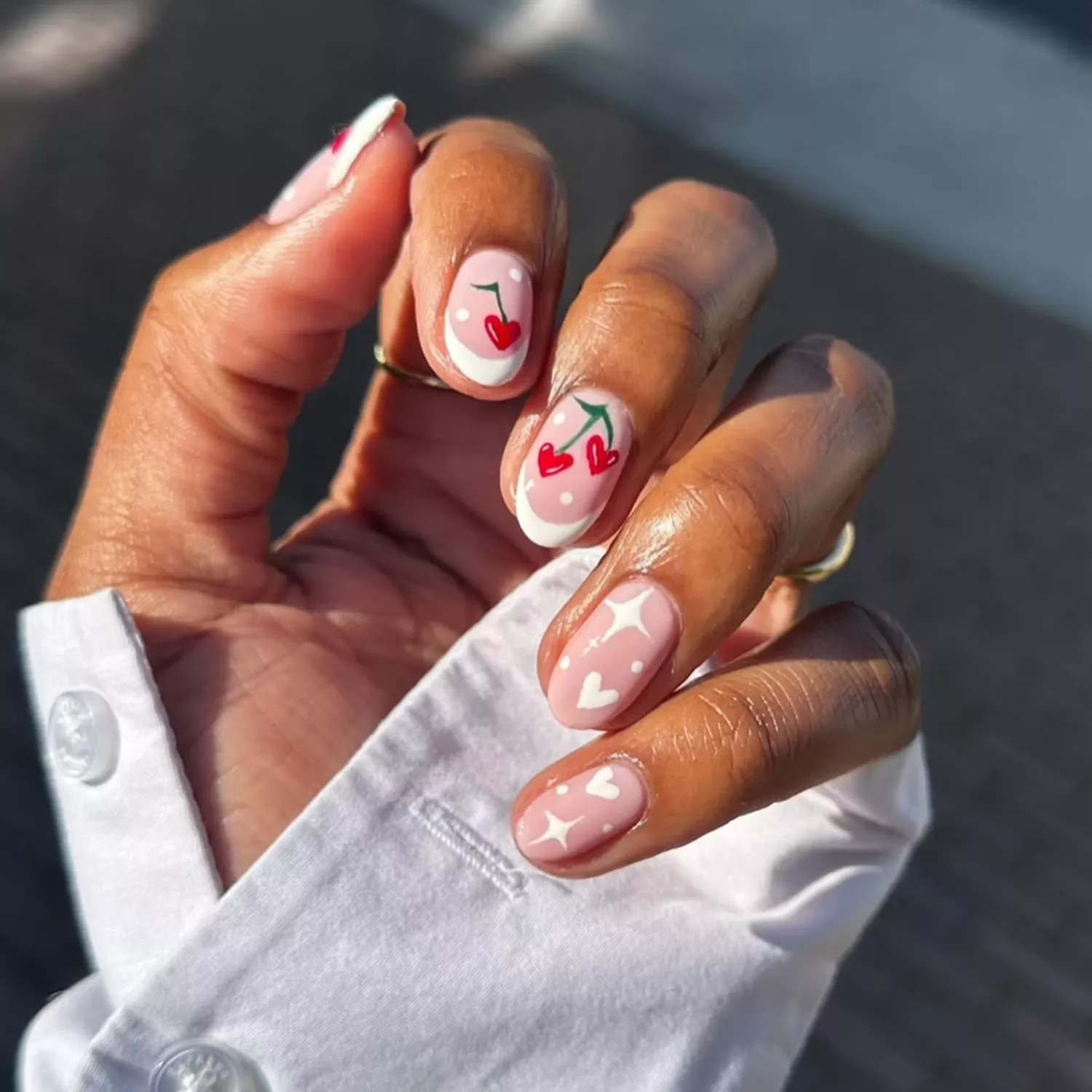 White French manicure with hand-drawn cherries, stars, and hearts