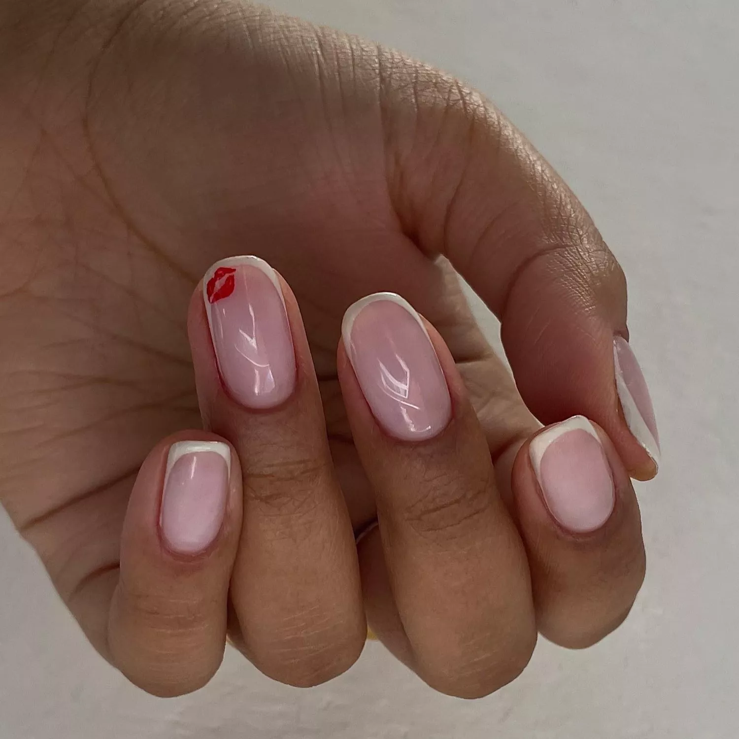 close up of short nail manicure with micro french and red kiss mark