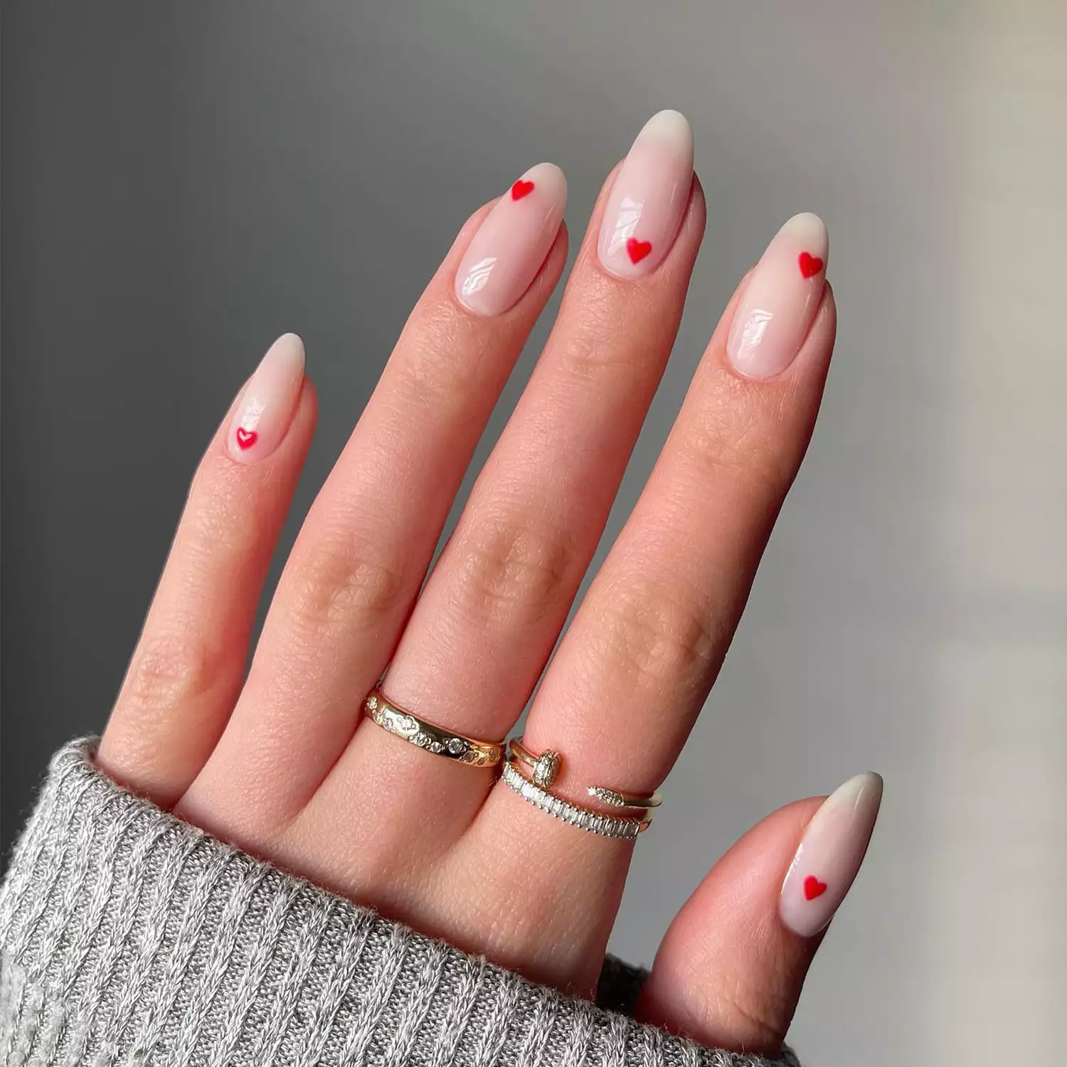 Long nude nails with mini red hearts