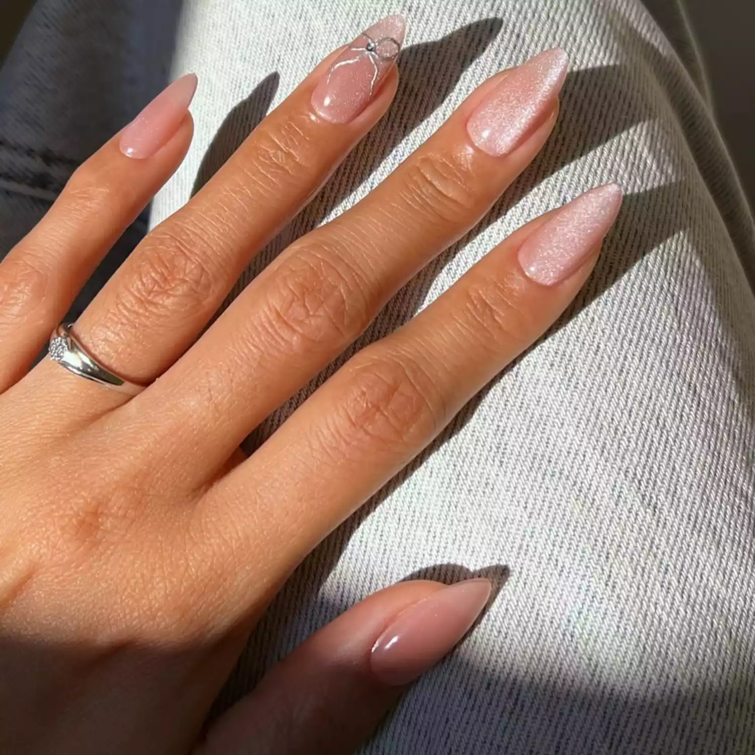 Long almond-shaped pink glitter chrome nails with silver bow detail