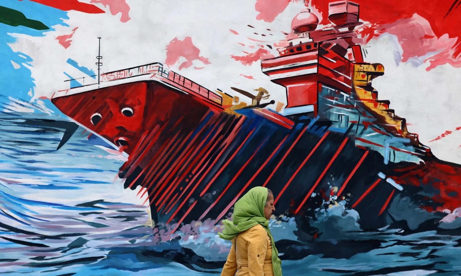 This photo taken on April 8, 2026 shows a woman walking past an anti-USA and anti-Israel mural, in Tehran. — AFP/File