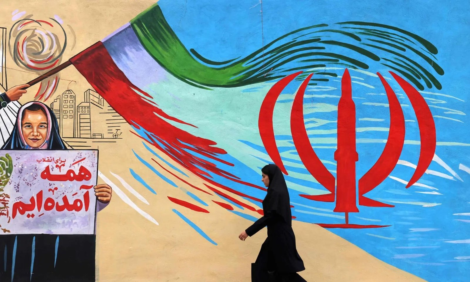 An Iranian woman walks past an anti-USA and anti-Israel mural, in Tehran on April 21 2026. — AFP