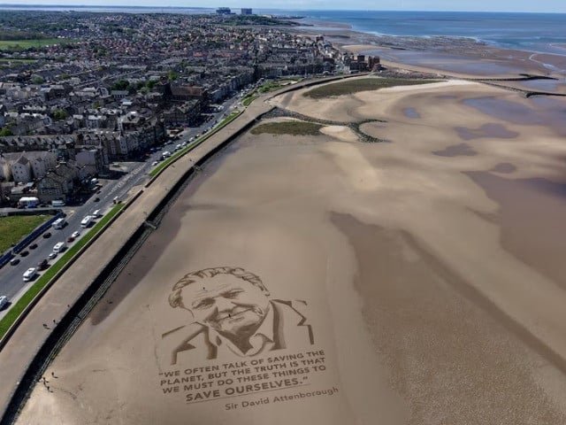A drone view shows artists from the Sand In Your Eye art team putting the finishing touches to a giant sand portrait of David Attenborough to mark the conservationist's 100th birthday, on the beach in Morecambe, Britain, May 6, 2026. REUTERS/Phil Noble Purchase Licensing Rights