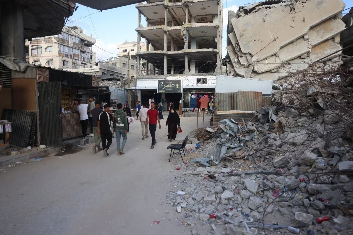Palestinian make their way past the rubble of buildings destroyed in Israeli military strikes, as they shop on the eve of the Muslim holiday of Eid al-Adha, or Feast of Sacrifice, marking the end of the Hajj pilgrimage, in Khan Yunis southern of Gaza Strip on May 26, 2026. AFP