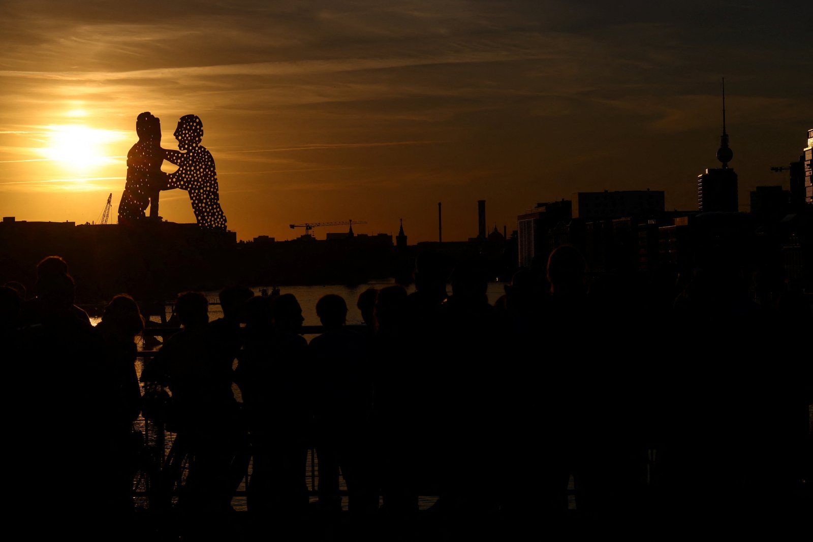 The partial eclipsed sun appears behind the 'Molecule Men', a 30-metre high metal sculpture by Jonathan Borofsky, located in Berlin's Spree river, Germany, August 12, 2026. Photo: Reuters