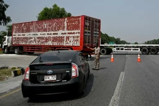 A police officer diverts traffic on the Islamabad–Peshawar Motorway blocked with trucks placed by authorities in Islamabad on September 24, 2026 ahead of PTI protest demanding the release of founder Imran Khan.